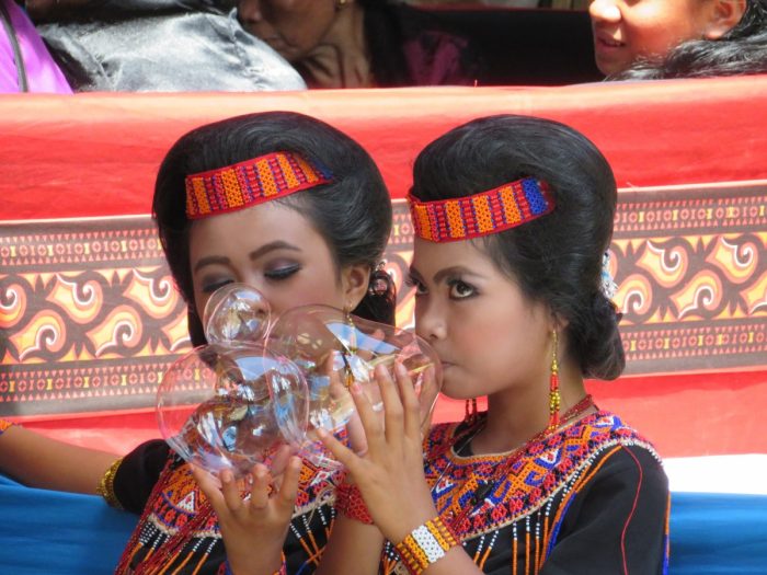 twee jonge meiden in traditionele kleding blazen bellen van suikergoed